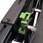 Close-up shot of a green metal adjustment mechanism on a black aluminum extrusion monitor mount, showing screws, sliding blocks, and mechanical details.